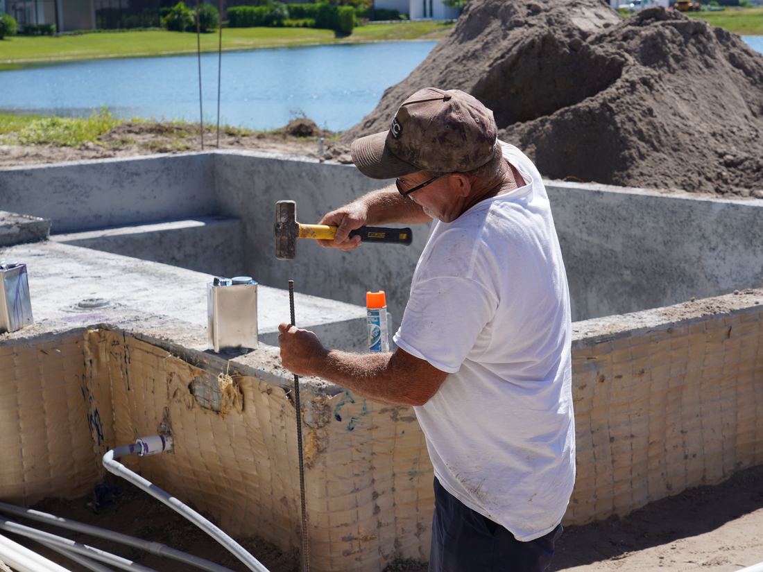 Ben setting rebar beside a new pool shell in Naples