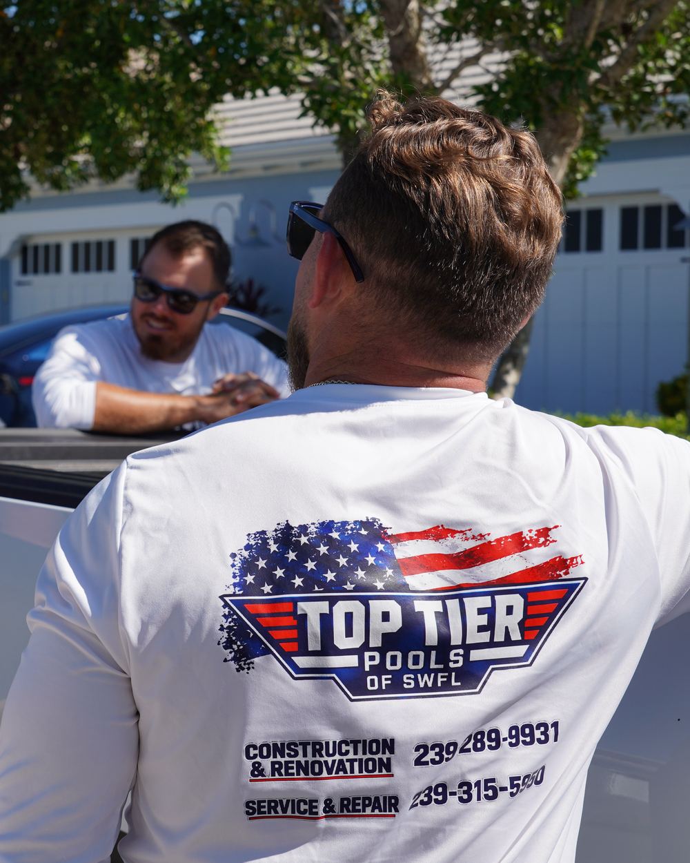 Top Tier Pools crew shirt showing construction and service phone numbers