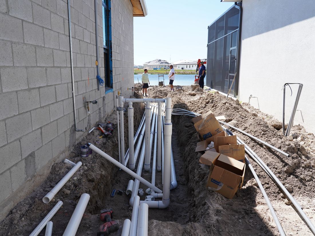 Underground pool plumbing laid out and pressure tested at a Naples new build