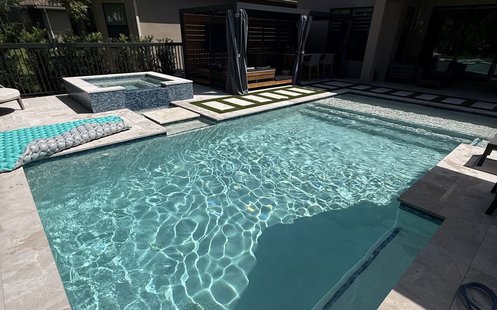 Raised spa beside a travertine pool deck and cabana